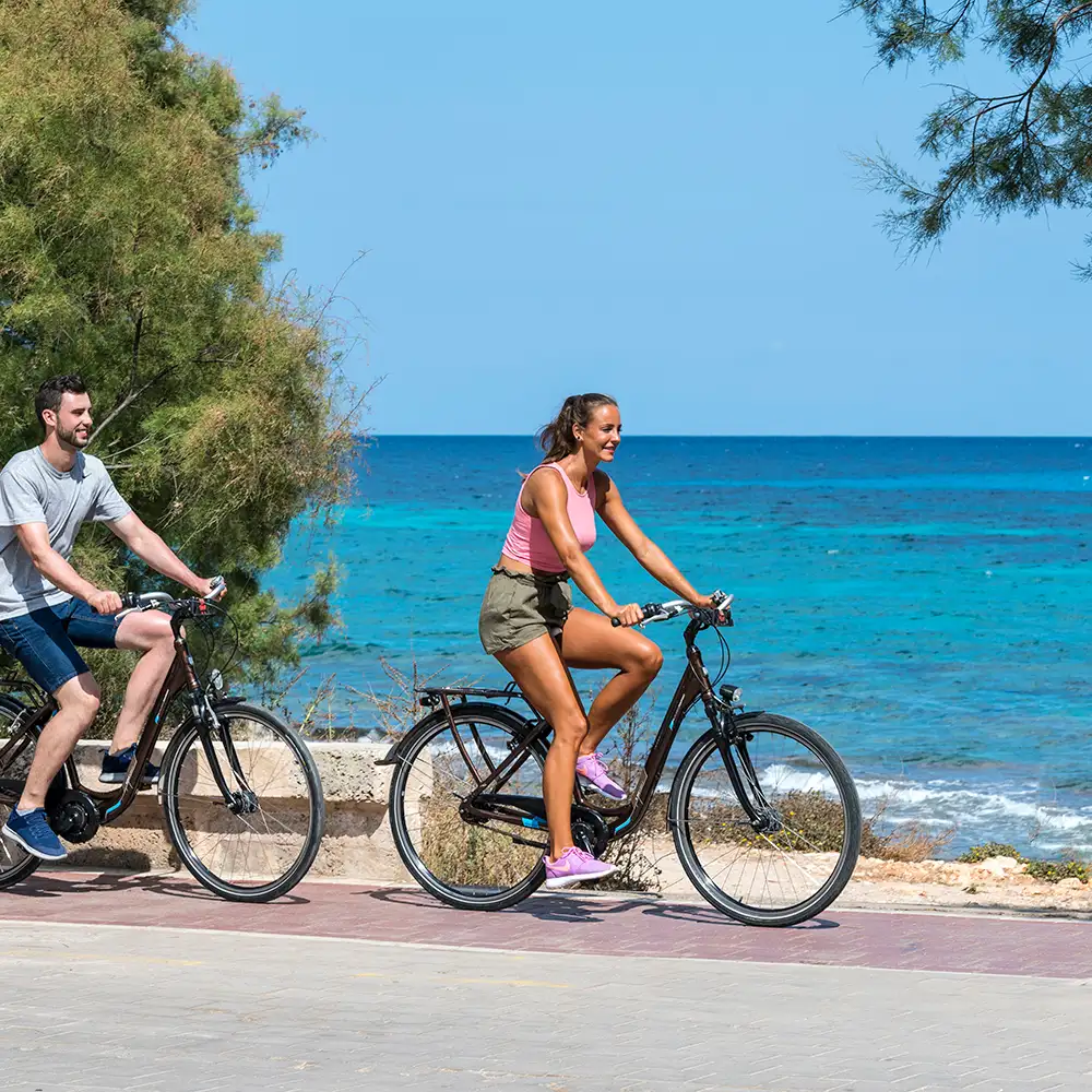 Pareja recorriendo en bicicleta el paseo de la playa junto al Hotel Mariant Park Mariant Hotels